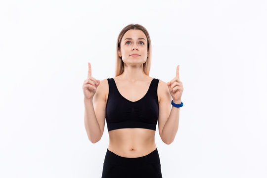 Young sporty blond woman in a black sportswear with smart watches for pulse measuring pointing with fingers up.