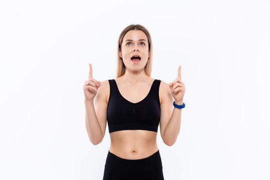 Young sporty blond woman in a black sportswear with smart watches for pulse measuring pointing with fingers up.