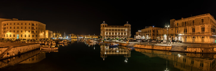 Fototapeta na wymiar Night panoramic view over the island Ortygia and its harbour with boats by night, city of Syracuse, Sicily, south Italy