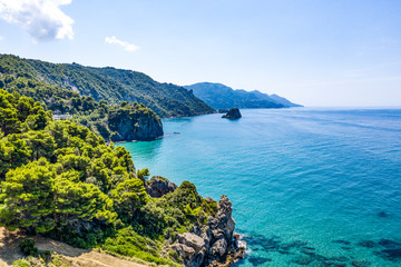 Aerial view of green seashore and turquoise sea water. Island with green trees in the ocean seen form above.