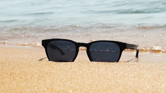 Sunglasses on beach. Sea waves, sunny day. Concept of holiday, vacation, relaxation, day at seaside