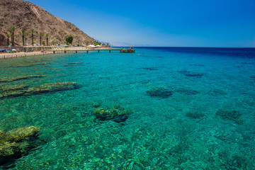 Obraz premium beautiful clean ecological place in the Earth with with coral beach and riffs, vivid transparent water and relaxing people near sea on wooden pier