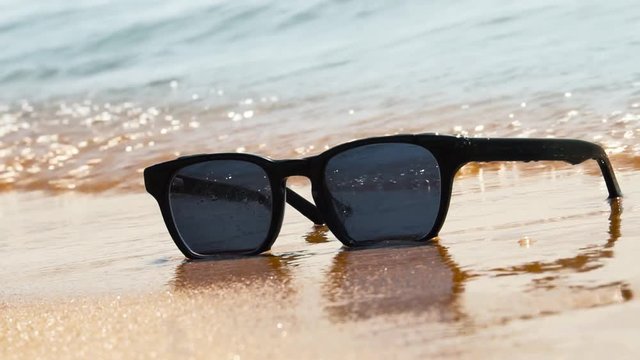 Sunglasses on beach. Sea waves, sunny day. Concept of holiday, vacation, relaxation, day at seaside