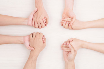 Fototapeta premium Close-up of young people sitting at the table and holding hands they support each other or playing in some game