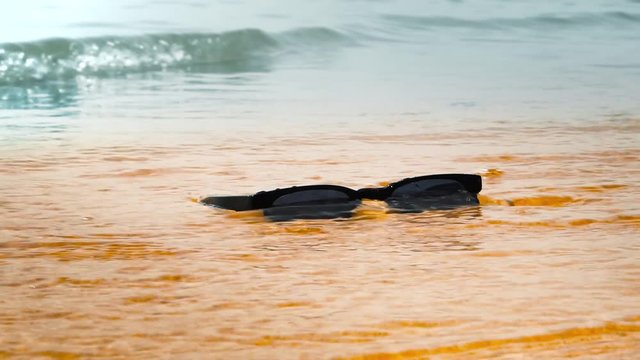 Sunglasses on beach. Sea waves, sunny day. Concept of holiday, vacation, relaxation, day at seaside