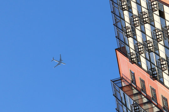 Airplane flying low in a blue sky over residential buildings. Commercial twin-engine plane landing above the residential area of a city, noise conception