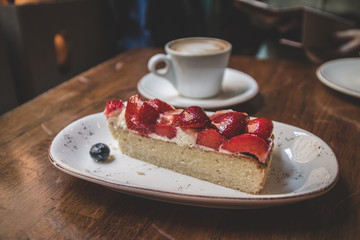 Close up strawberry cake with coffee latteon a wooden vintage table