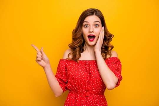 Pretty lady indicating fingers empty space showing black friday prices wear red dress isolated yellow background