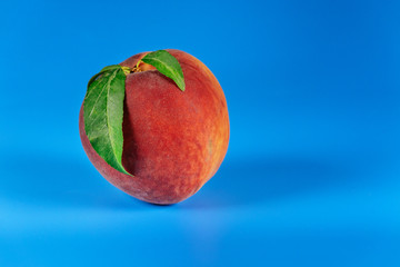 Peach with leaves isolated on blue background