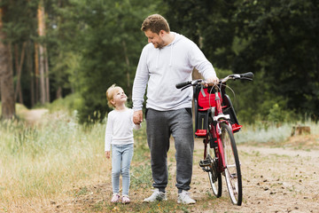 Father and daughter walking next to bike