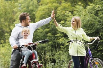 Family on bicycles giving high five