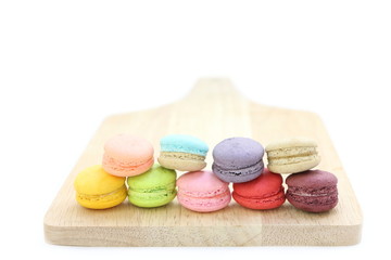 Close up many colorful fresh macarons pile isolated on wood chopping board on white background, look delicious