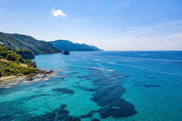 Fototapeta premium Aerial view of green seashore and turquoise sea water. Island with green trees in the ocean seen form above.
