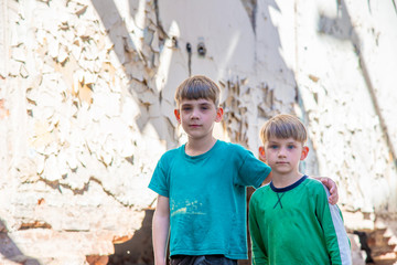 Obraz na płótnie Canvas Children in an abandoned and destroyed building in the zone of military and military conflicts. The concept of social problems of homeless children. Staged photo.