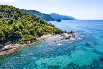 Fototapeta premium Aerial view of green seashore and turquoise sea water. Island with green trees in the ocean seen form above.