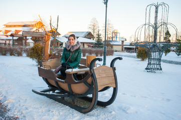 The girl on the winter sled, large sled for skiing. Girl riding a reindeer sleigh.