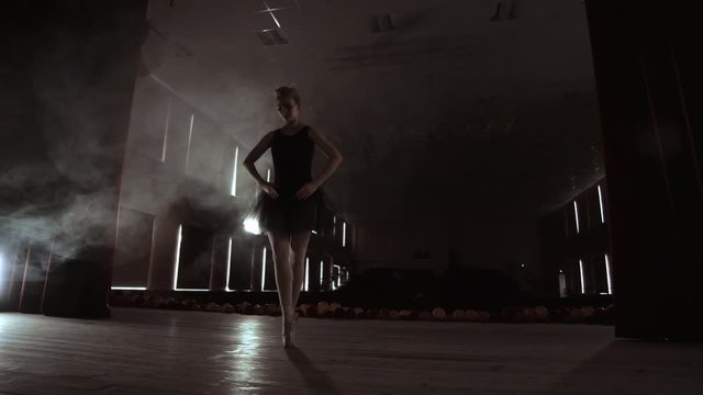 Prima ballerina on pointes training on stage with spotlights in late evening before important performance in Opera and Ballet theatre. Indoors