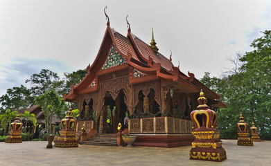 Side of brown teak wood carving temple  (Wat khao chawang) in rainy season in Chantaburi, Thailand