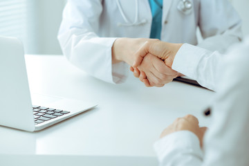 Doctor and patient shaking hands, close-up. Medicine, healthcare and trust concept