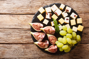 Mediterranean antipasti appetizer of cheese, fresh grapes and figs close-up on a slate board. horizontal top view