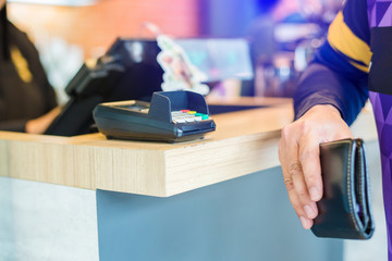 Selective focus to credit card reader with blurry wallet in hand of man. self service payment in...