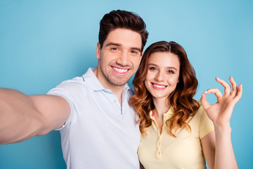 Close up photo of foxy lady brunet guy pair making selfies fingers okey symbol wear casual t-shirts isolated blue background