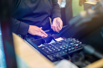 The cashier is picking up banknotes and coins inside the cash register machine. Cashier staff receive and change money to customers in the store.