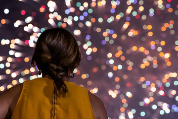 Mujer joven de espaldas mirando los fuegos artificiales. San Juan, solsticio de verano. Nocturna.