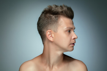 Fototapeta na wymiar Profile portrait of shirtless young man isolated on grey studio background. Caucasian healthy male model looking at side and posing. Concept of men's health and beauty, self-care, body and skin care.