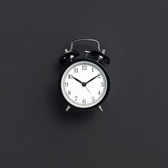 Black retro alarm clock on gray dark background top view Flat lay copy space. Minimalistic...