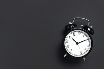 Black retro alarm clock on gray dark background top view Flat lay copy space. Minimalistic...