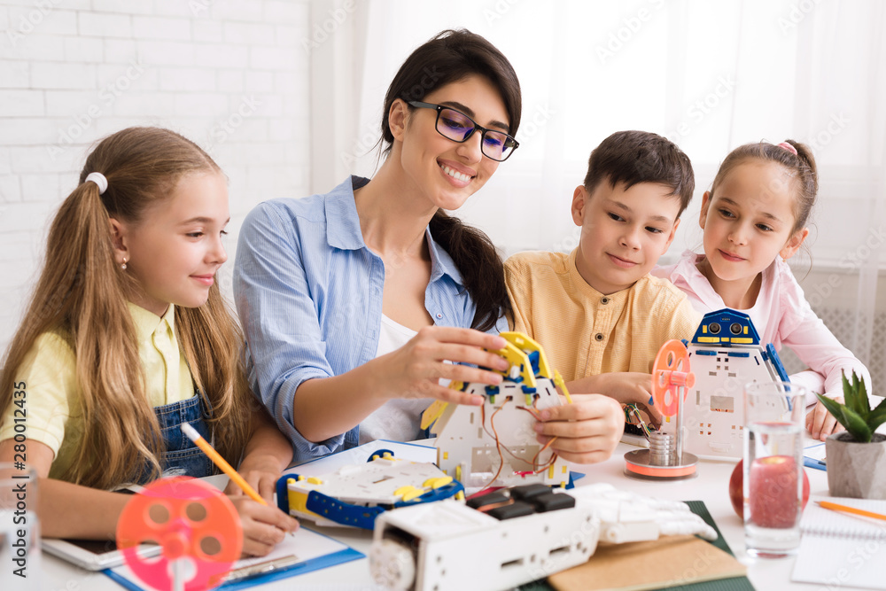 Poster kids creating robots with teacher at stem education class