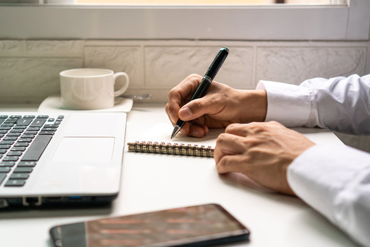 Businessman is taking a note on the notebook  from the financial imformation from laptop computer.business work concept.