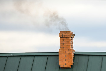 Smoke from the chimney, heating. smoke billowing. coming out of a house chimney against a blue sky...