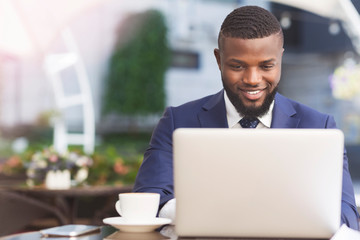 Smiling African American Businessman Working On Laptop In Outdoor Cafe