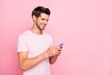 Profile side view portrait of his he nice attractive cheerful cheery concentrated guy holding in hands device web surfing using dating service isolated over pink pastel background
