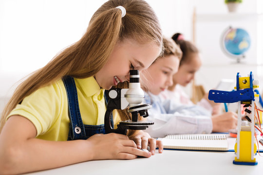 Stem education. Little girl looking at microscope