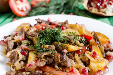 beef with vegetables and herbs on a white plate close-up sharpness in the foreground