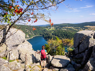 Rear view of women hiker looking at view of forest from Hans rock edge above Lac Blanc at Rocher Hans, France