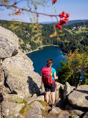 Rear view of women hiker looking at view of forest from Hans rock edge above Lac Blanc at Rocher Hans, France