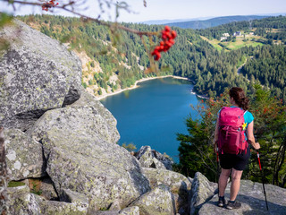 Rear view of women hiker looking at view of forest from Hans rock edge above Lac Blanc at Rocher Hans, France