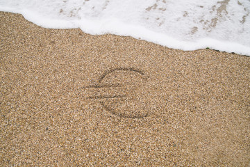 euro sign drawn on the wet sand, washed by sea waves