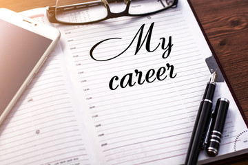 A business notebook (a diary) and  business accessories (mobile phone, glasses, a fountain pen) with text my career