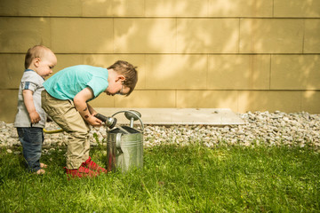 Two little boys in the garden filling watering can