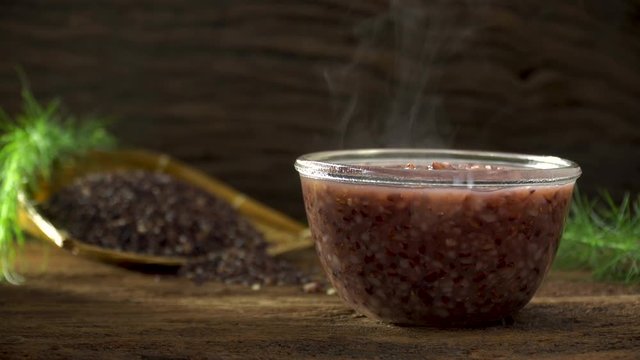 Close up of boiled rice berry in bowl on wooden table. Rice berry on background. Food and healthy concept.