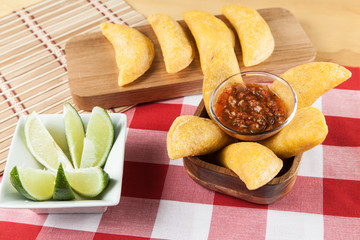Tasty colombian food, fried empanada; photo on wooden background.