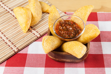 Tasty colombian food, fried empanada; photo on wooden background.