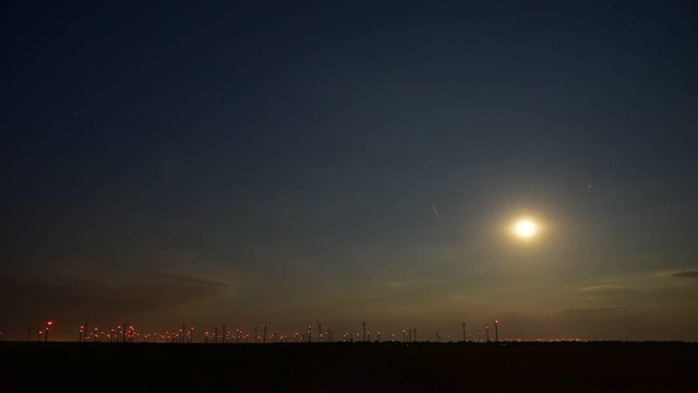 Full moonrise time-lapse over the Burgenland plain with flashing red lights from wind turbines to generate green electricity at night.