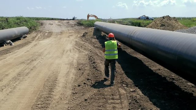 Worker With Radio Communication Device Walking at Oil Pipeline Construction Site