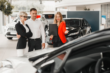 Dealer showing a car. Couple  choose and  buying the auto  - Image